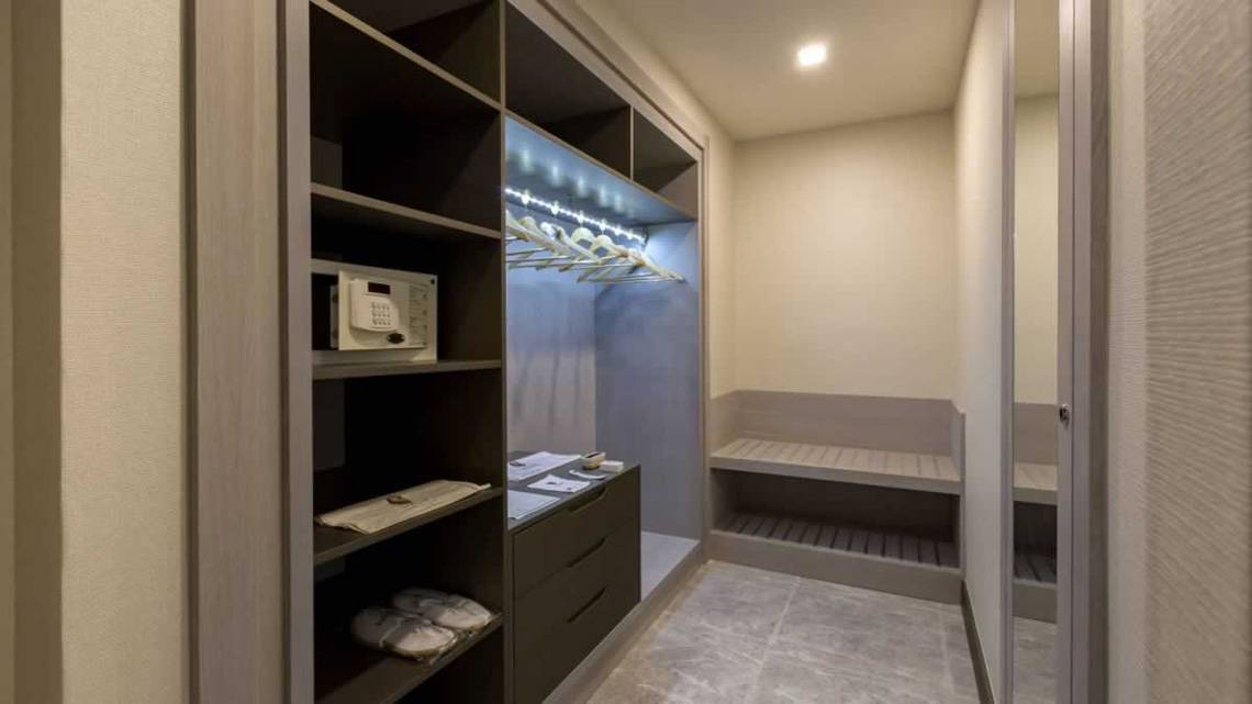 Ein moderner begehbarer Kleiderschrank im Royal Seginus Hotel mit eingebautem Safe und Beleuchtung.