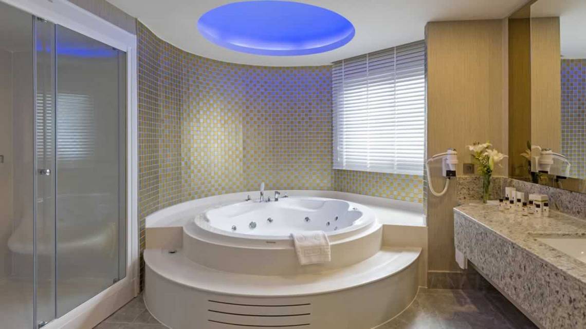 Badezimmer im Royal Seginus Hotel mit Jacuzzi und beleuchteter Decke.