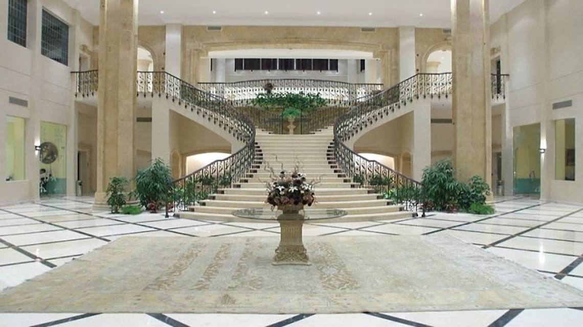 Foyer des Magic Tulip Resorts mit doppelten Treppen und einem Blumenarrangement.