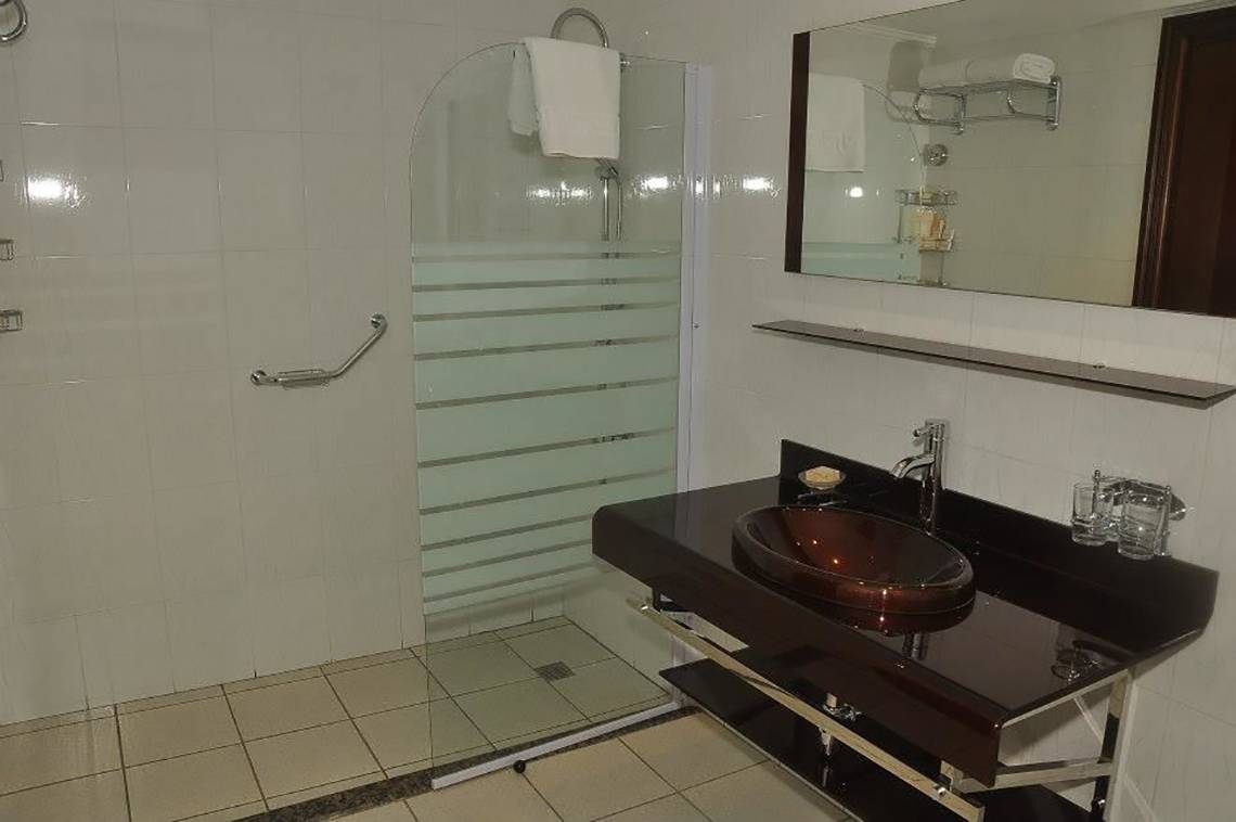 Badezimmer im Magic Tulip Resort mit Glasdusche, Waschbecken und Spiegel.