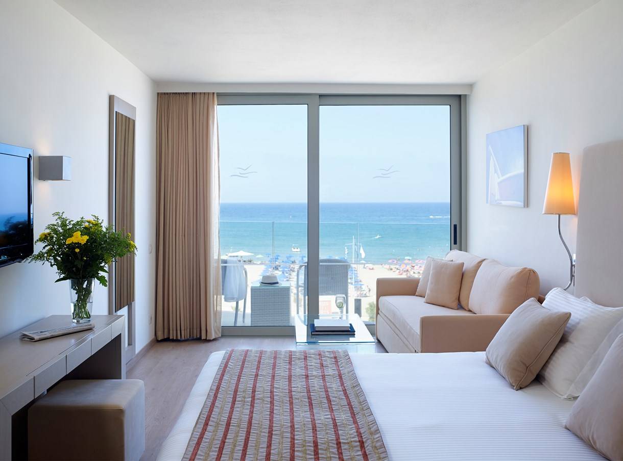Hotelzimmer im Kriti Beach mit Meerblick, inklusive Sofa, Bett, Fernseher und Dekor.
