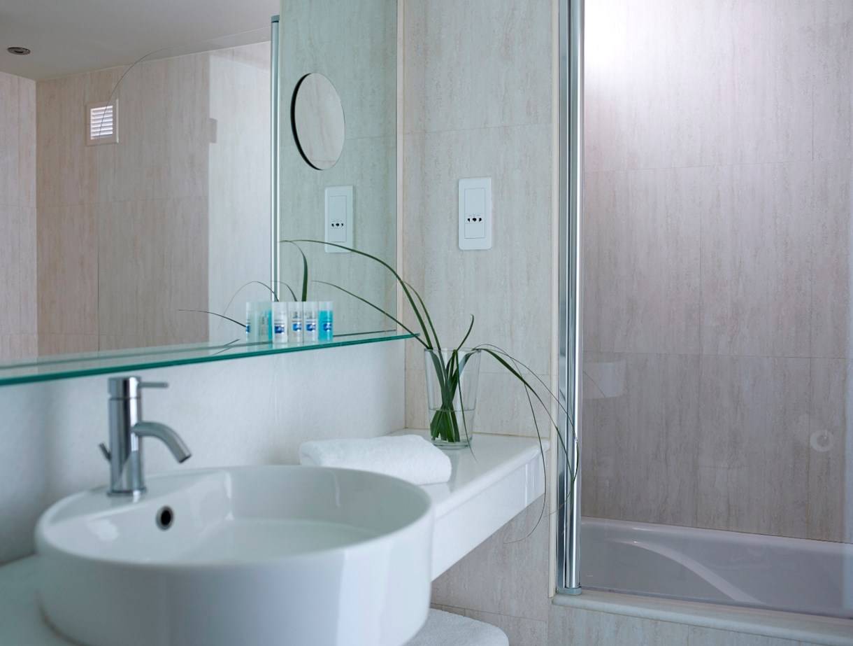 Kriti Beach Hotel Badezimmer mit einer weißen Wanne, einem Waschbecken und einem Spiegel.