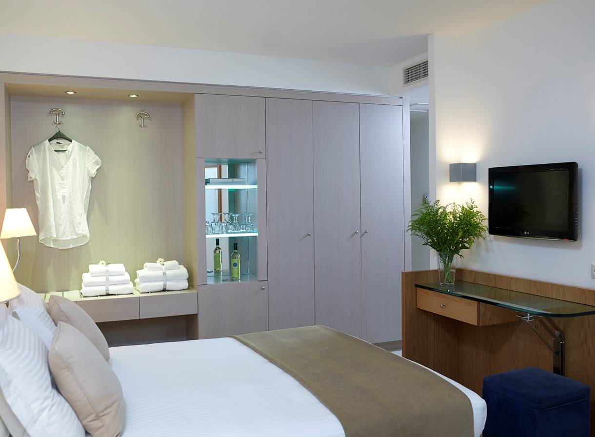 Schlafzimmer im Kriti Beach Hotel mit Bett, Kleiderschrank und Fernseher.