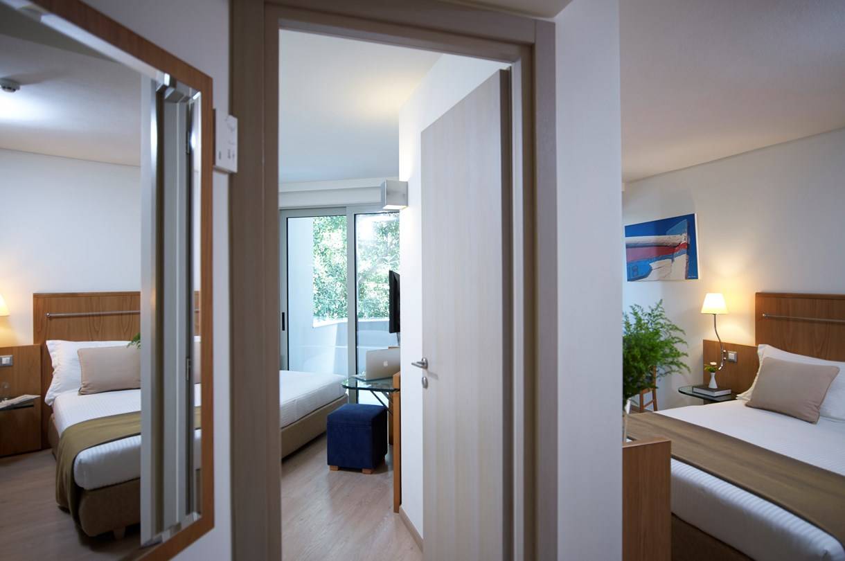 Zimmeransicht im Kriti Beach Hotel mit zwei Betten, Schreibtisch und Balkon.