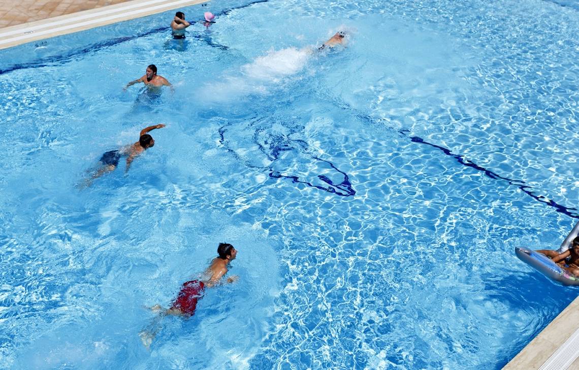 Mehrere Menschen schwimmen im blauen Pool des Altin Yunus Hotel & Spa.