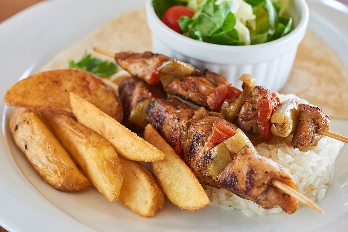 Ein Teller mit gegrilltem Fleisch, Pommes und Salat.