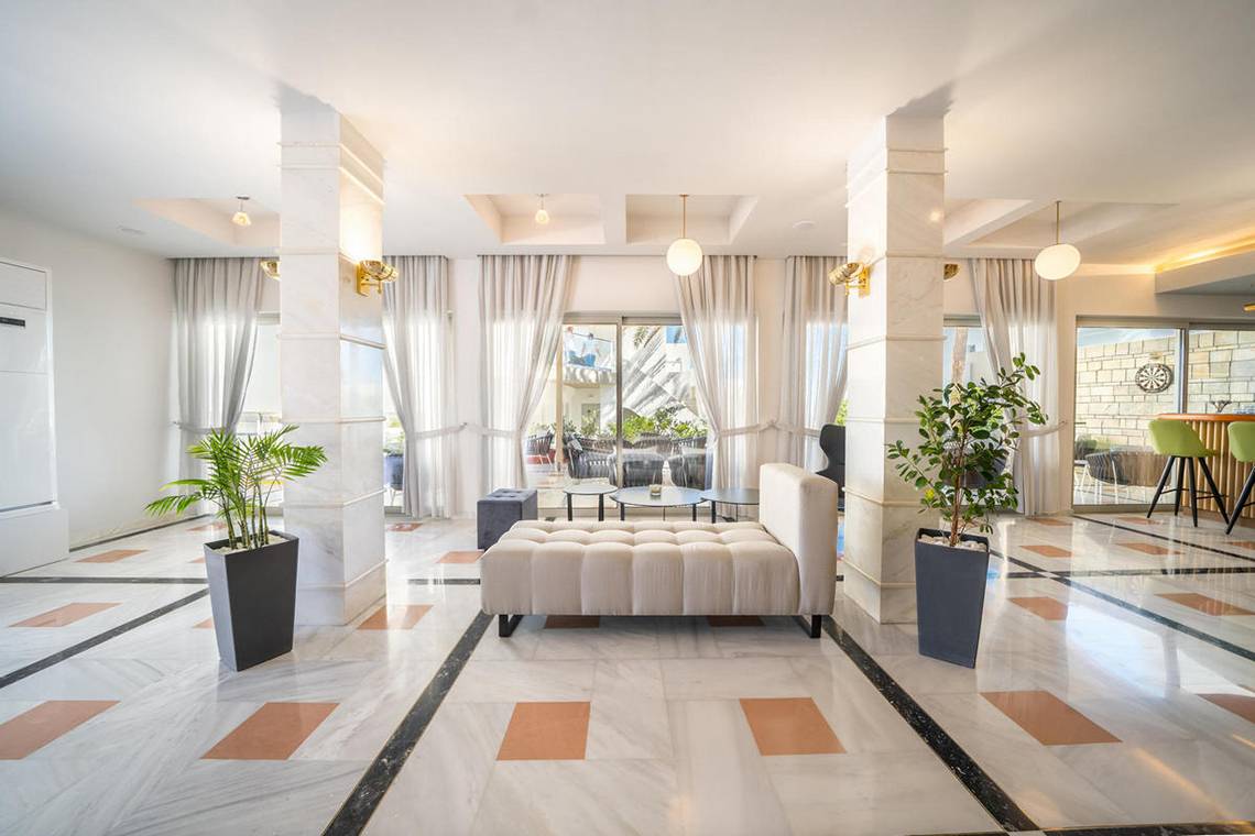 Empfangsbereich des Adele Beach Hotels mit weißem Marmorboden, hohen Säulen und modernen Möbeln.