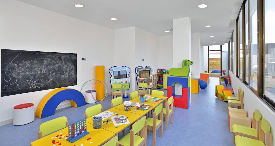 Kinderspielzimmer im NYX Ibiza Hotel mit bunten Möbeln, Spielgeräten und einer Tafel.