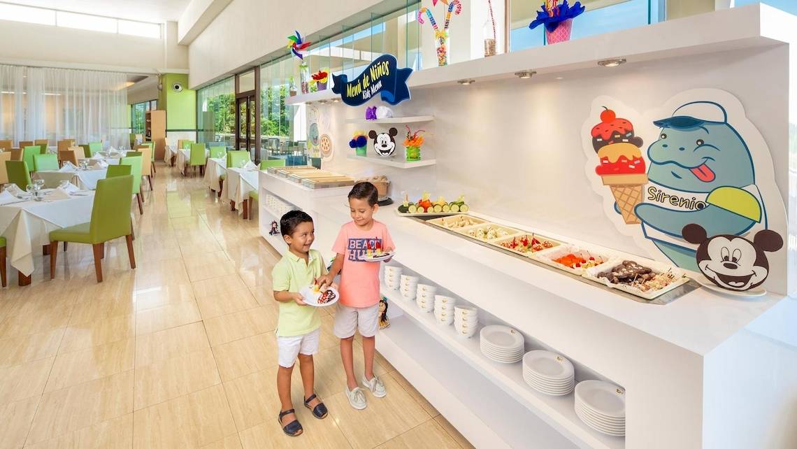 Zwei Kinder stehen vor einem Buffet im Grand Sirenis Riviera Maya Resort & Spa.