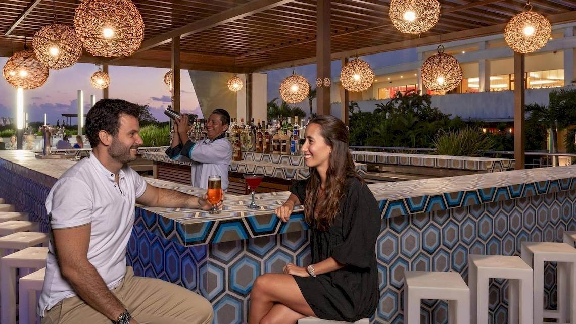 Ein Paar sitzt an einer Bar im Grand Sirenis Riviera Maya Resort & Spa und genießt Cocktails.