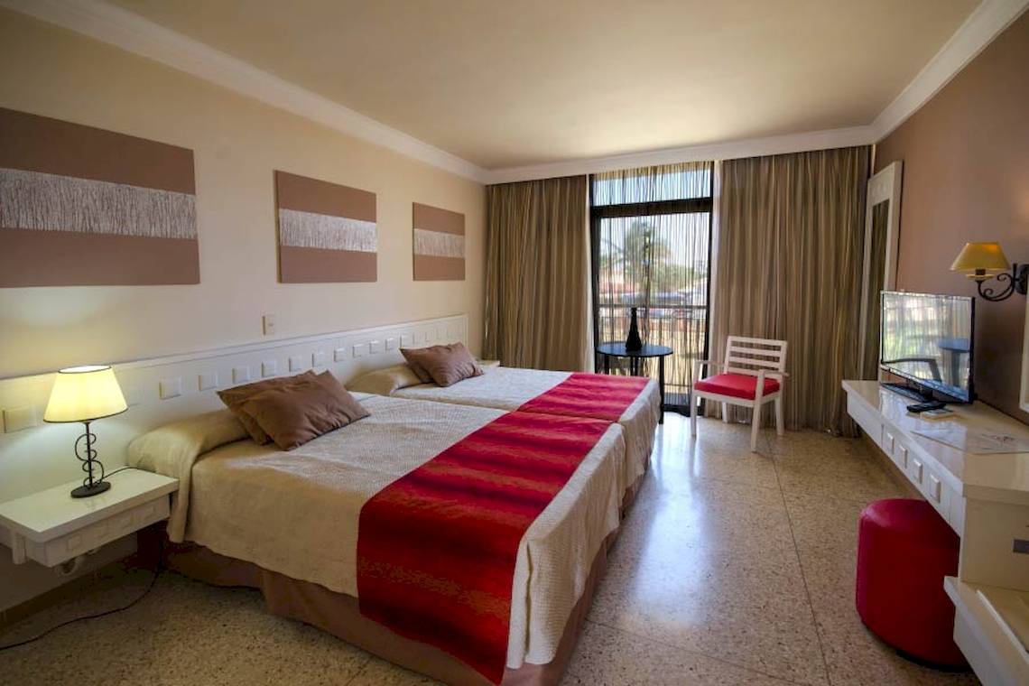 Zweibettzimmer im Roc Barlovento Hotel mit zwei Betten, Tisch, Fernseher und Balkon.