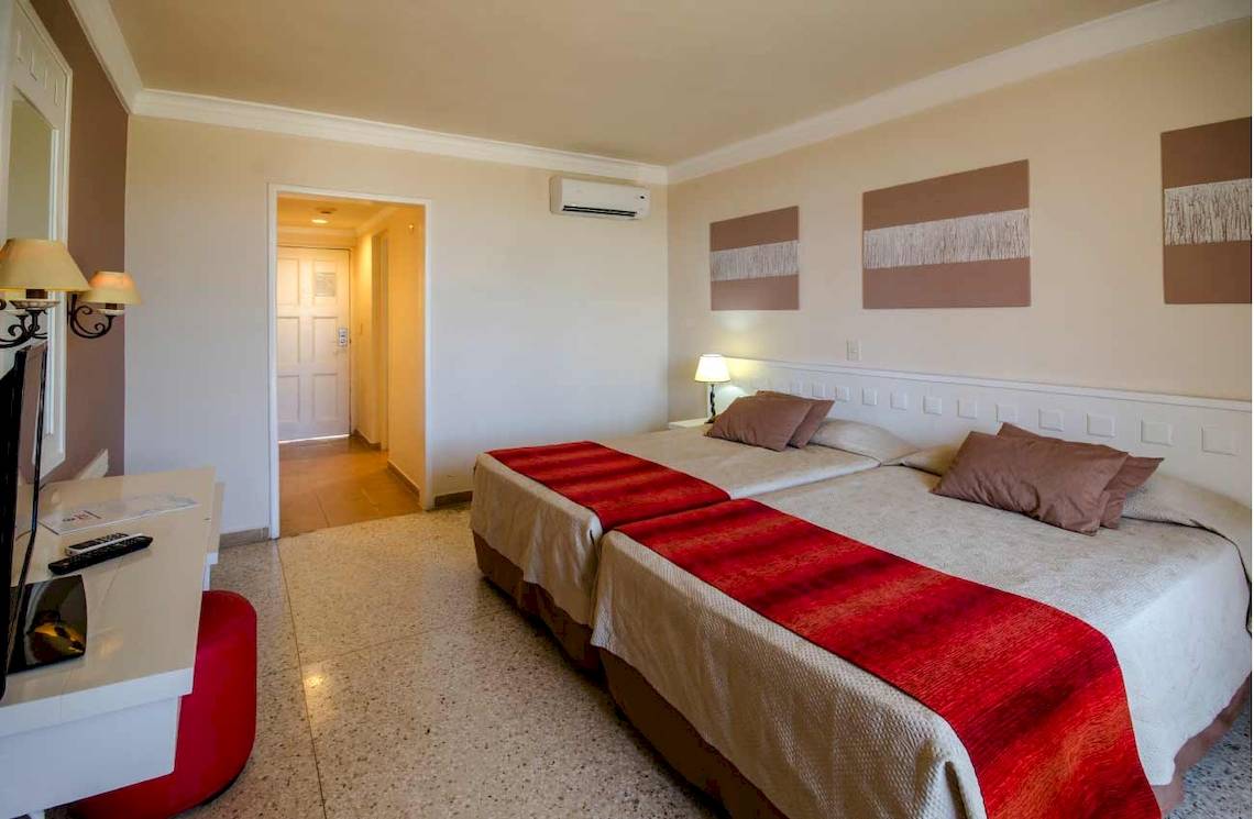 Doppelzimmer im Roc Barlovento Hotel mit zwei Betten, Fernseher und Nachttisch.
