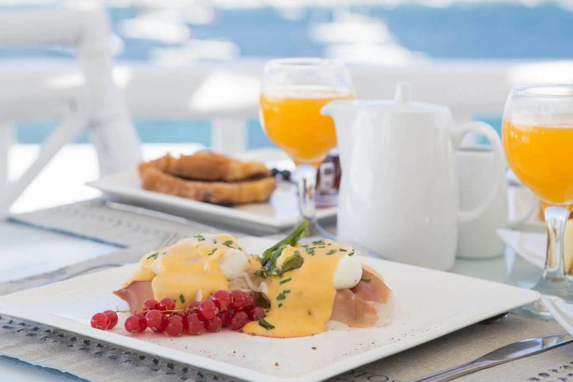 Frühstück im Kivotos Mykonos mit Eier Benedict, Toast, und Orangensaft.