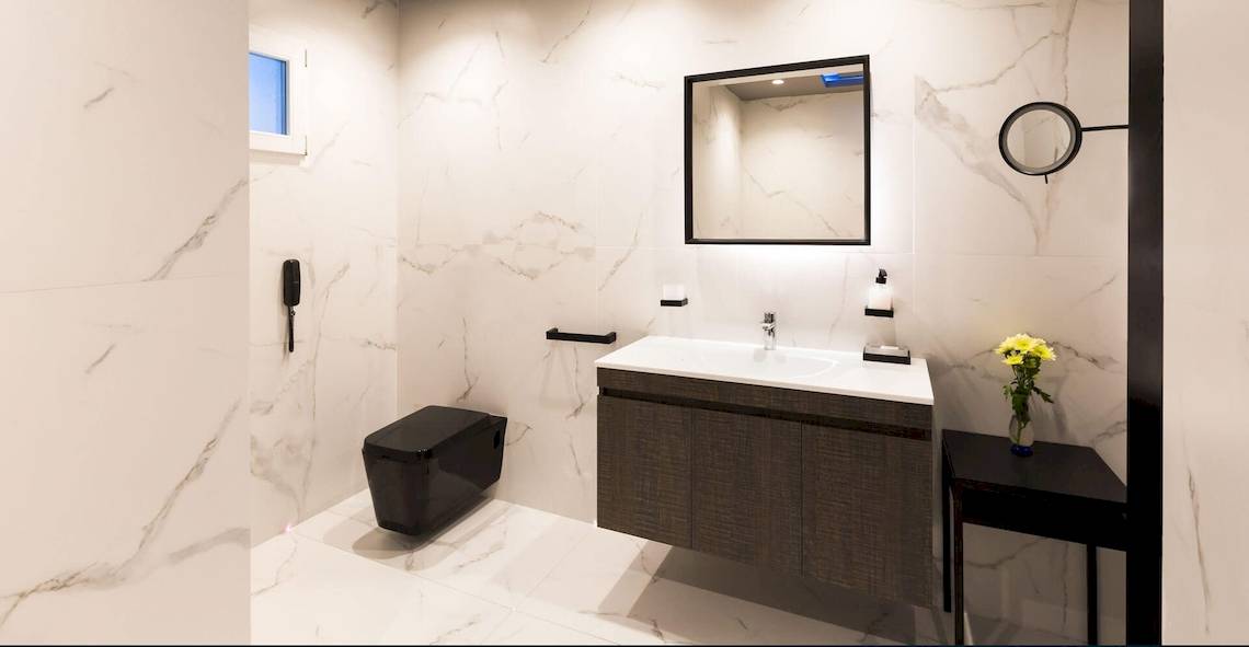 Ein modernes Badezimmer mit weißem Marmor und schwarzen Akzenten im Kivotos Mykonos Hotel.