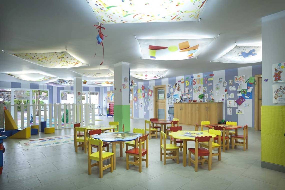 Kinderspielzimmer im Roca Nivaria Gran Hotel mit bunten Tischen, Stühlen und dekorativen Wandgestaltungen.