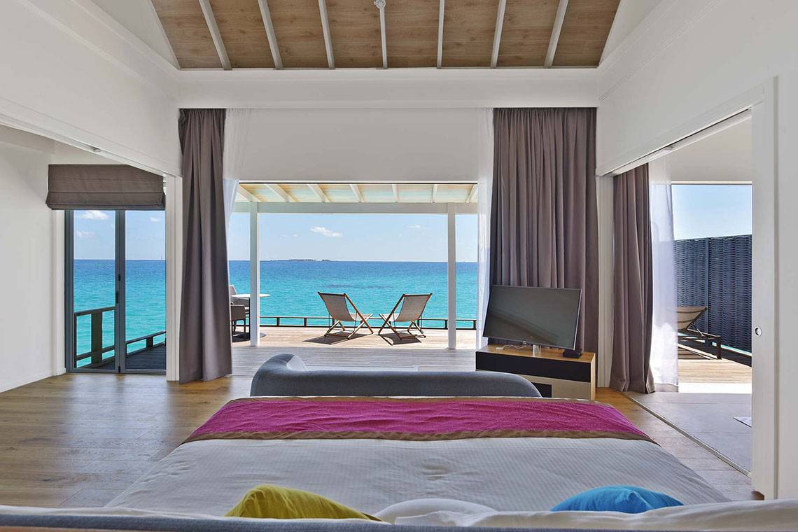 Suite im Kuramathi Maldives mit Blick auf das Meer und zwei Sonnenstühlen auf der Terrasse