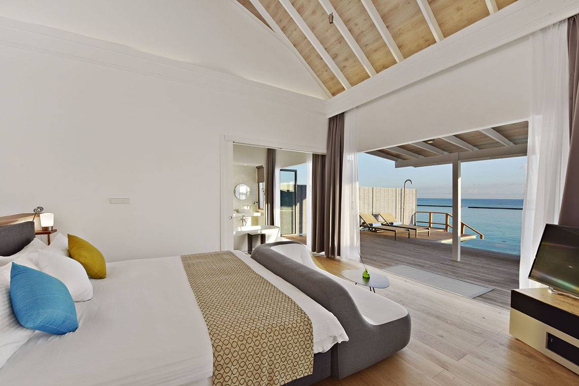 Schlafzimmer im Kuramathi Maldives Hotel mit Meerblick und Terrasse.