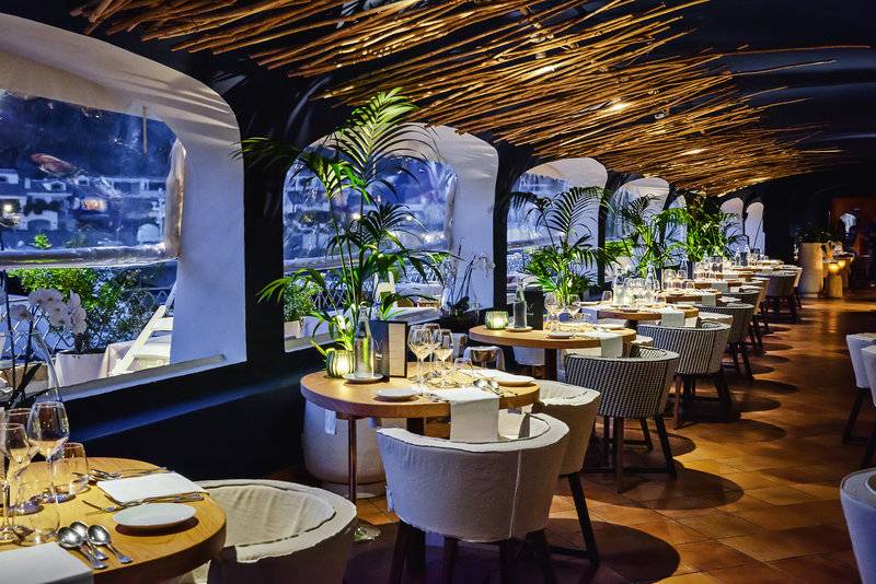 Innenansicht des Restaurants im Grand Hotel Poltu Quatu mit runden Tischen und Stühlen.
