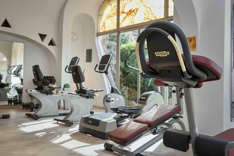 Fitnessstudio im Grand Hotel Poltu Quatu mit Technogym-Geräten und Glasfenstern