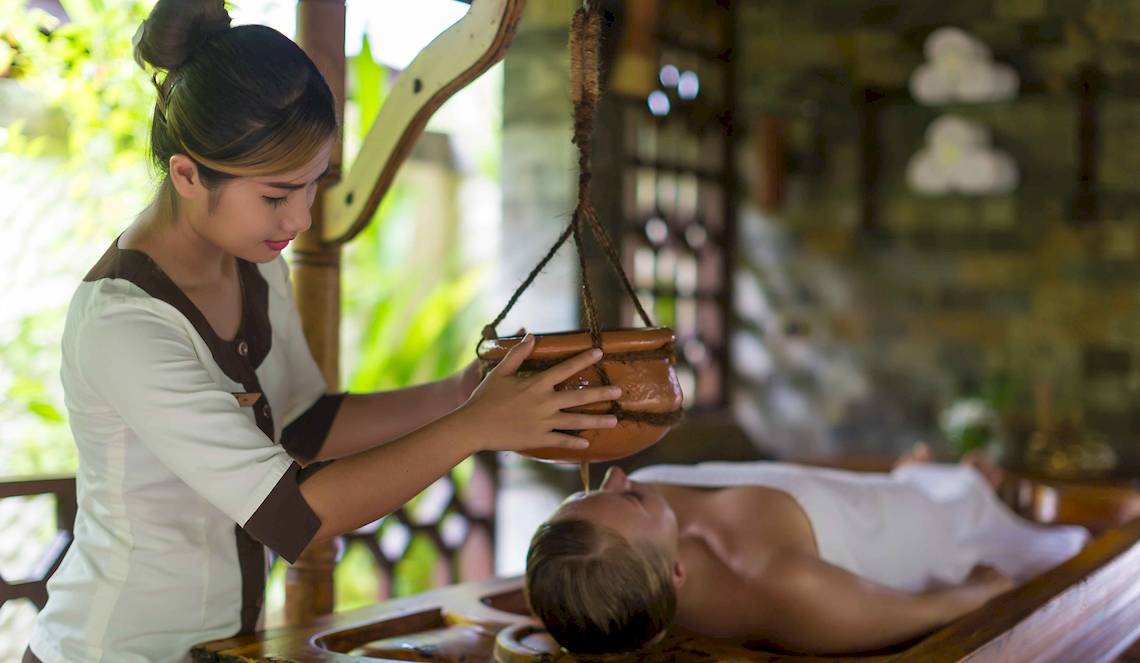 Eine Masseuse gibt einem Gast im Sun Siyam Olhuveli eine Kopfmassage.