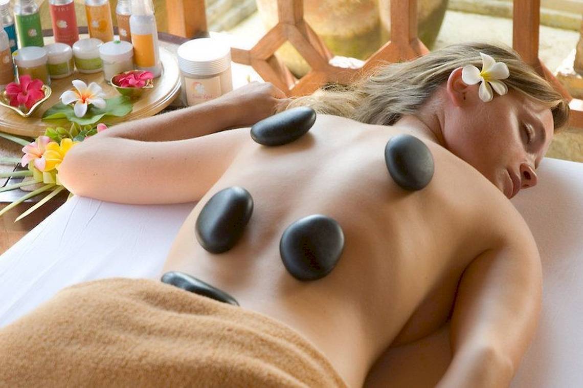Frau genießt eine Steinmassage im Sun Siyam Olhuveli Hotel