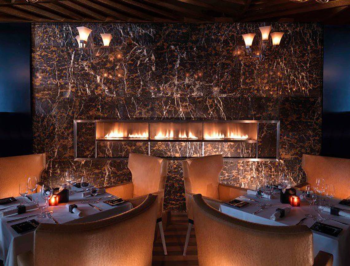 Interieur des Fairmont Bab Al Bahr Restaurants mit Marmorwänden und einer großen Feuerstelle.