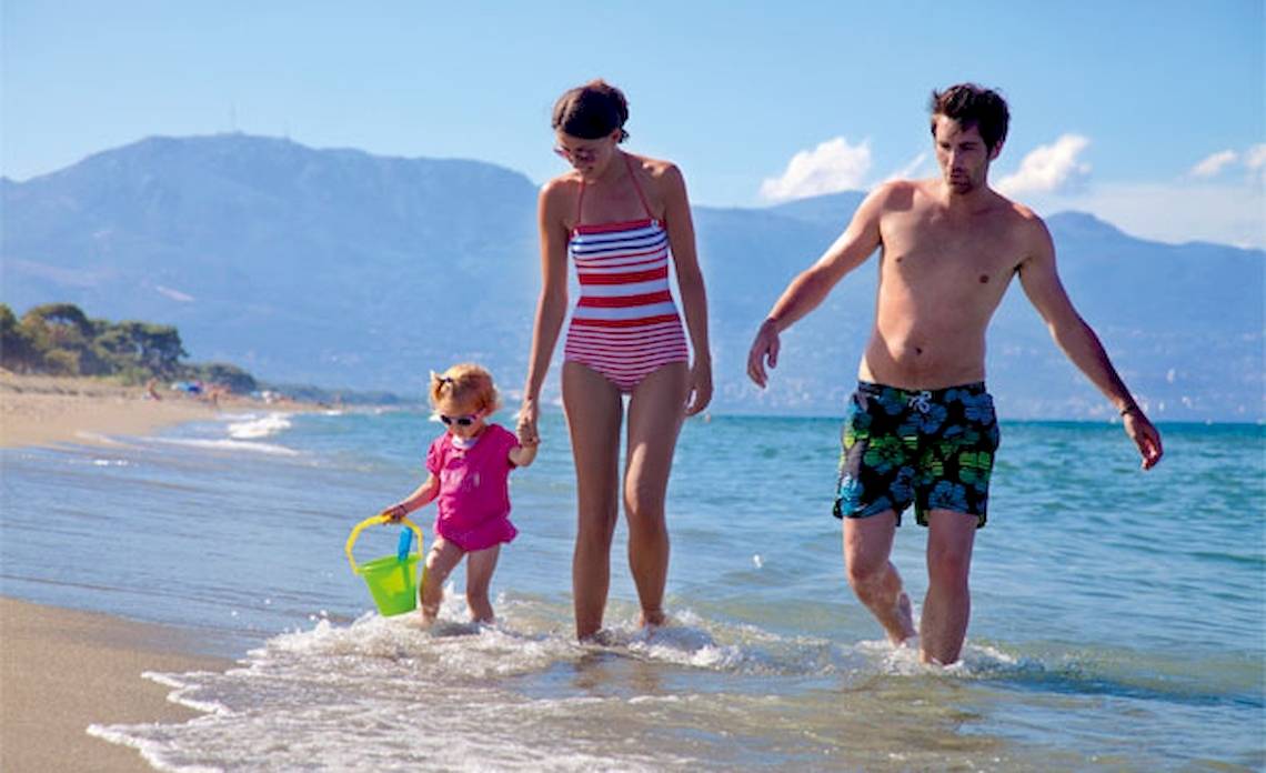 Familie am Strand von Belambra Clubs Pineto, ein Erwachsener und ein Kind gehen ins Wasser.