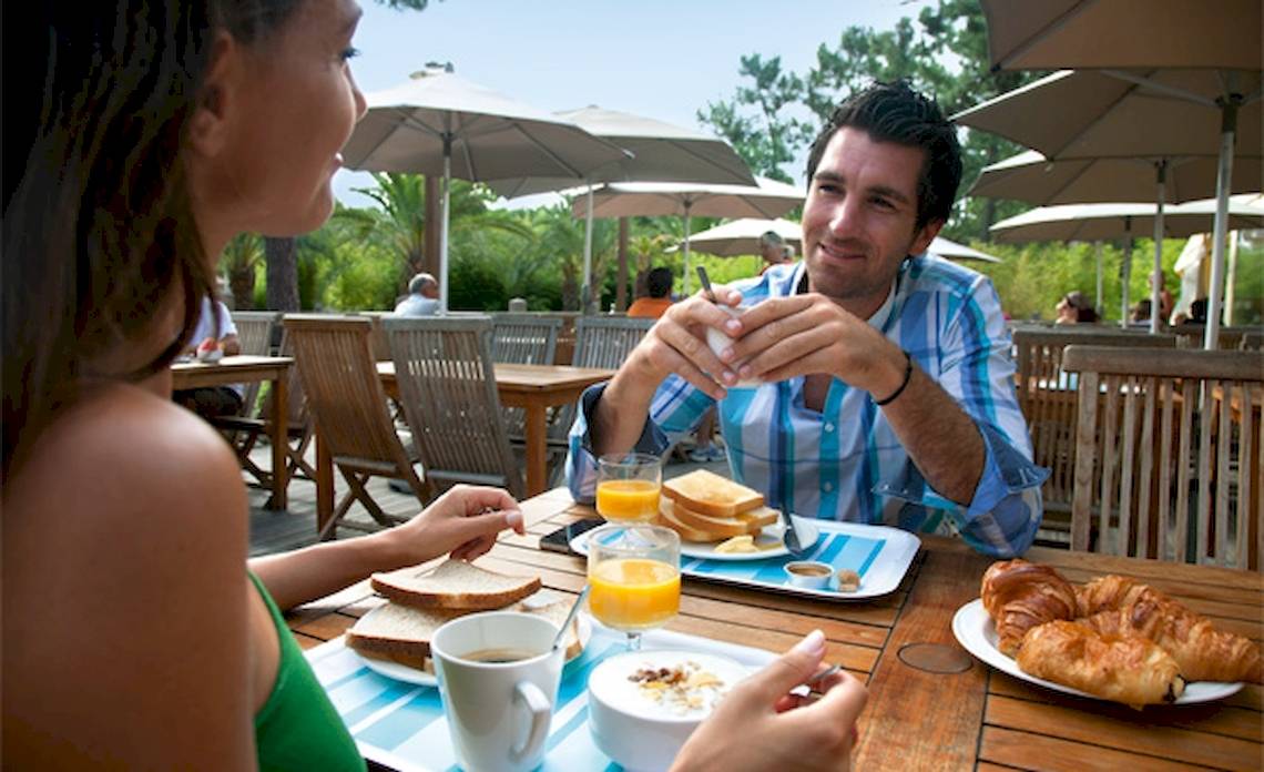 Frühstück im Belambra Clubs Pineto mit Mann und Frau, Croissants, Toast und Orangensaft.