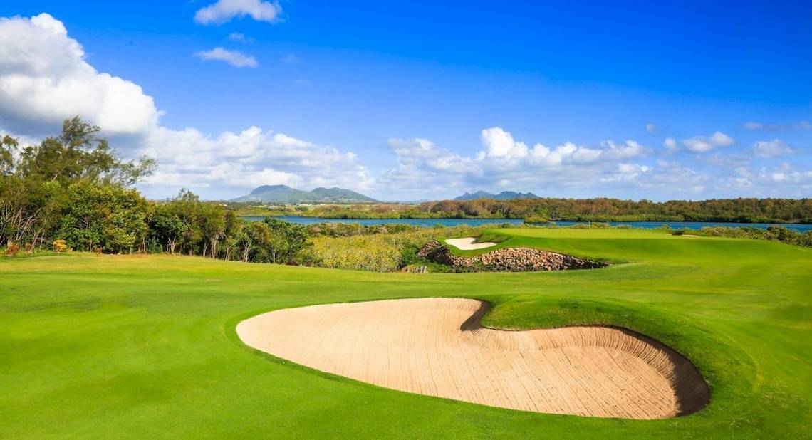 Golfplatz bei La Pirogue Mauritius mit Wasserhindernis und blauem Himmel