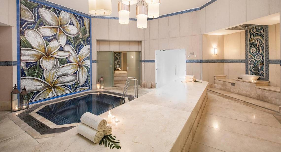 Wellnessbereich im La Pirogue Mauritius Hotel mit Swimmingpool, Kerzen und blauen Wandfliesen.