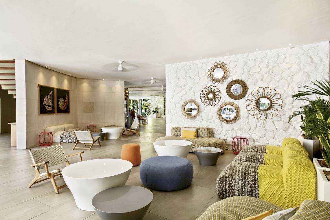 Lobby des La Pirogue Mauritius Hotels mit weißen Wänden, bunten Möbeln und Dekorationen.