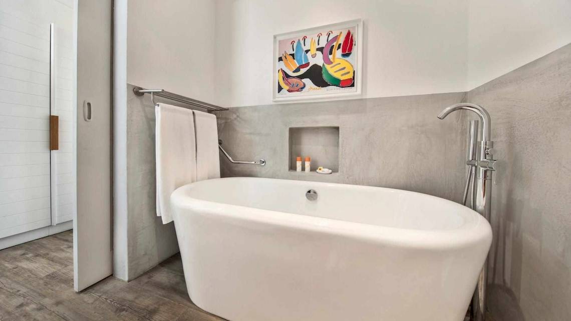 Das Badezimmer des La Pirogue Mauritius Hotels mit Badewanne, Handtuchhalter und Gemälde an der Wand.