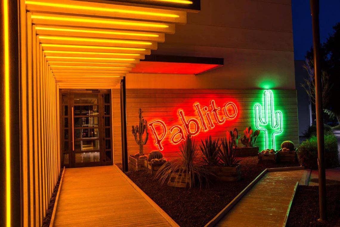 Eingang des Akra Hotels mit leuchtendem Schild und Kakteen in der Nacht