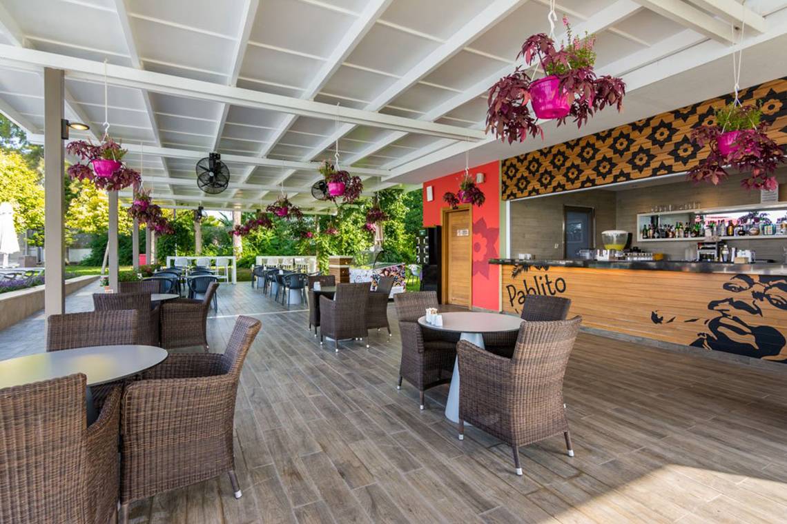 Terrasse des Akra Hotels mit Tischen, Stühlen und Pflanzen