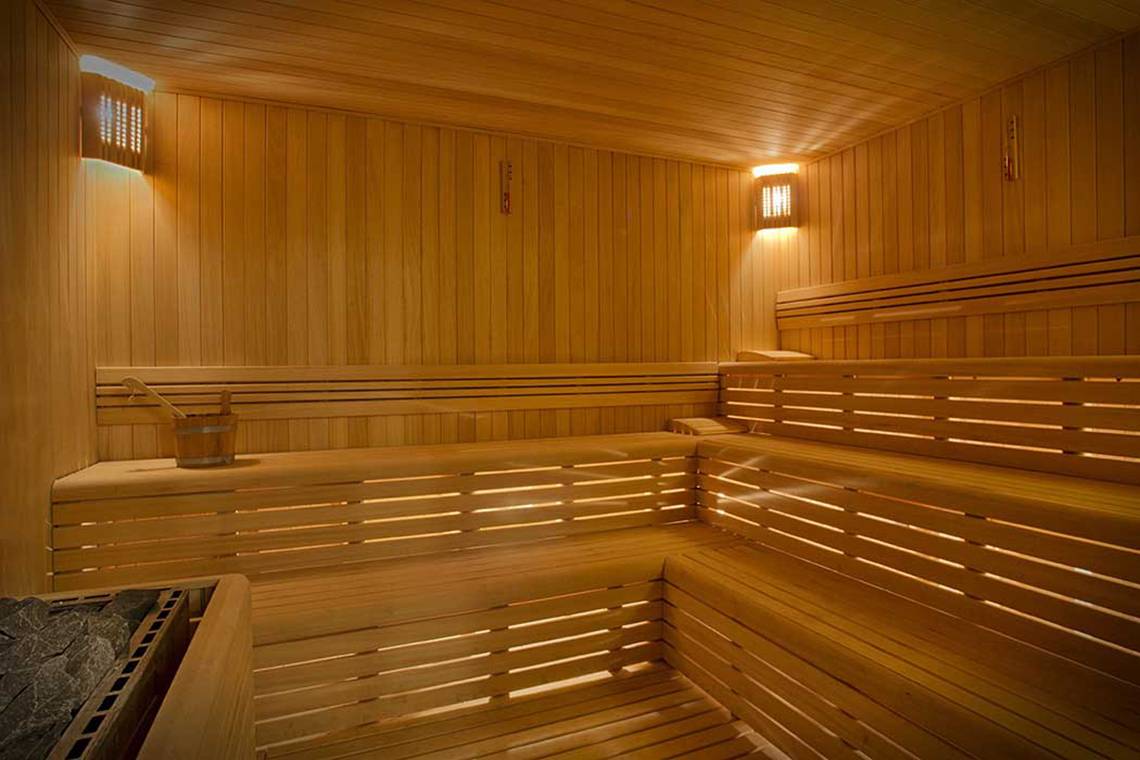 Innenansicht der Sauna im Akra Hotel mit hölzernen Bänken und warmem Licht.