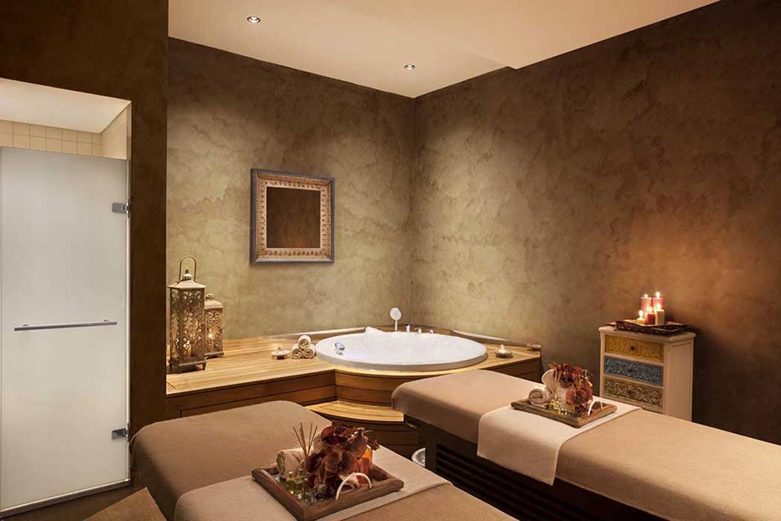 Spa-Behandlungsraum im Akra Hotel mit Rundbad, Massageliegen und Kerzen.