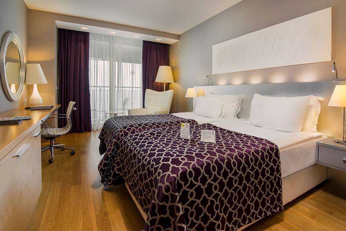 Schlafzimmer im Akra Hotel mit zwei Betten, Nachttischen und Schreibtisch