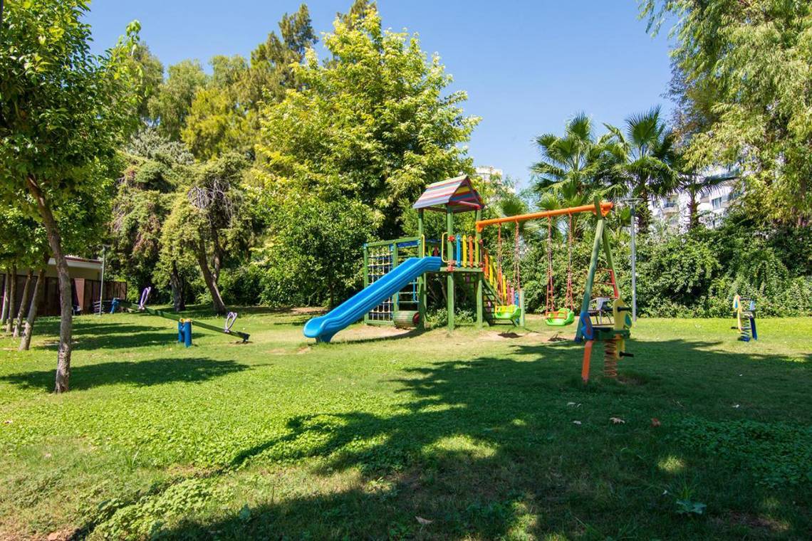 Kinderspielplatz im Garten des Akra Hotels mit Rutsche und Schaukeln.