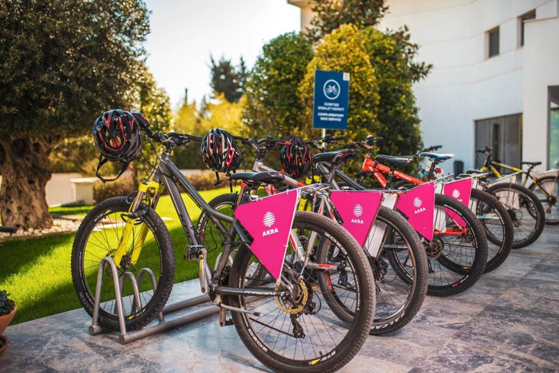 Mehrere Fahrräder mit pinken Bannern, die vor dem Akra Hotel geparkt sind.