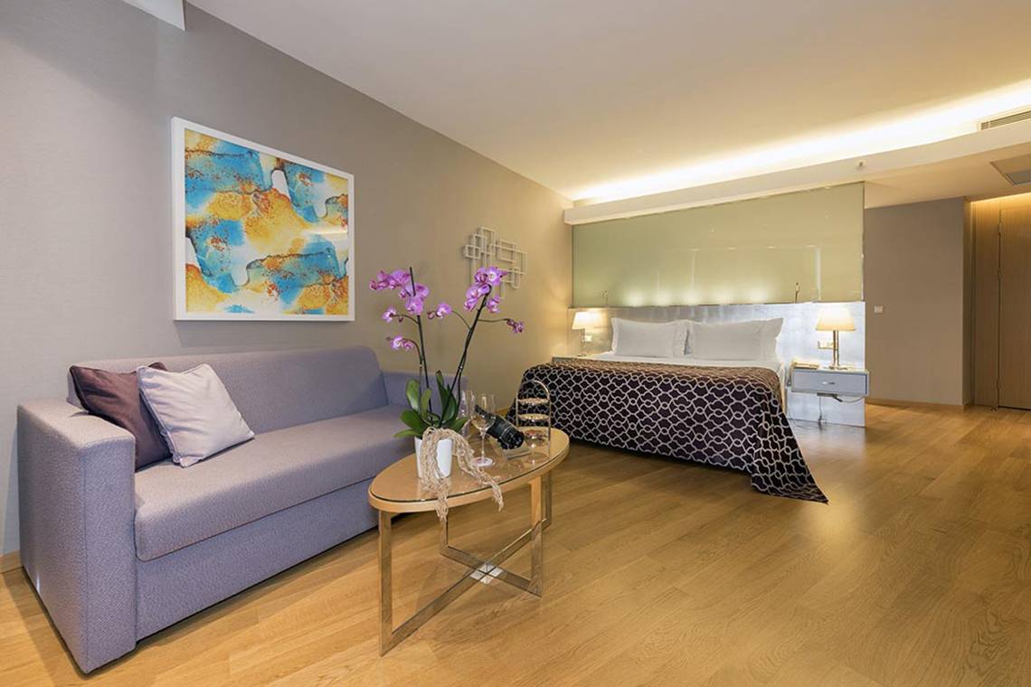 Hotelzimmer im Akra Hotel mit Doppelbett, Sofa und modernem Dekor.