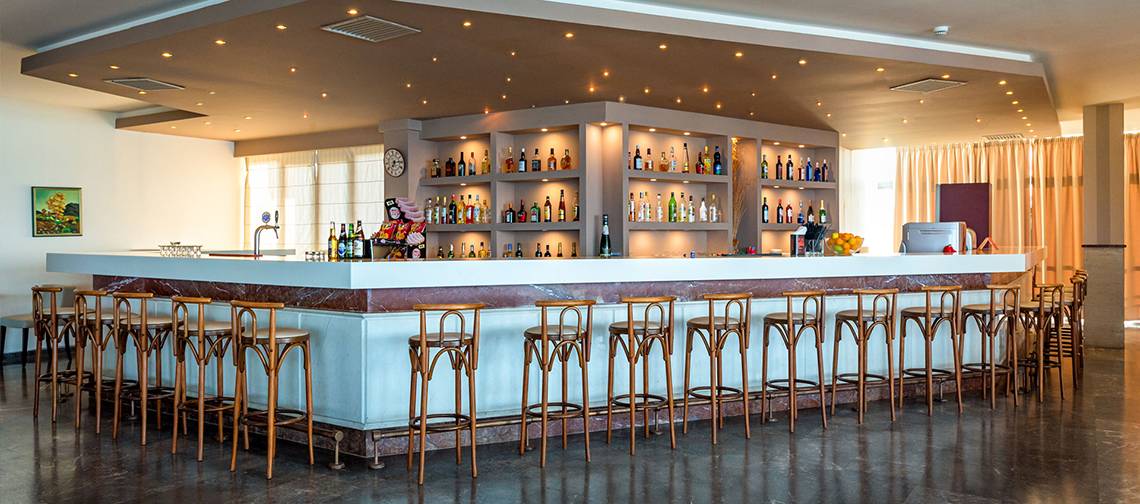 Barbereich im Themis Beach Hotel mit vielen Flaschen und Stühlen.