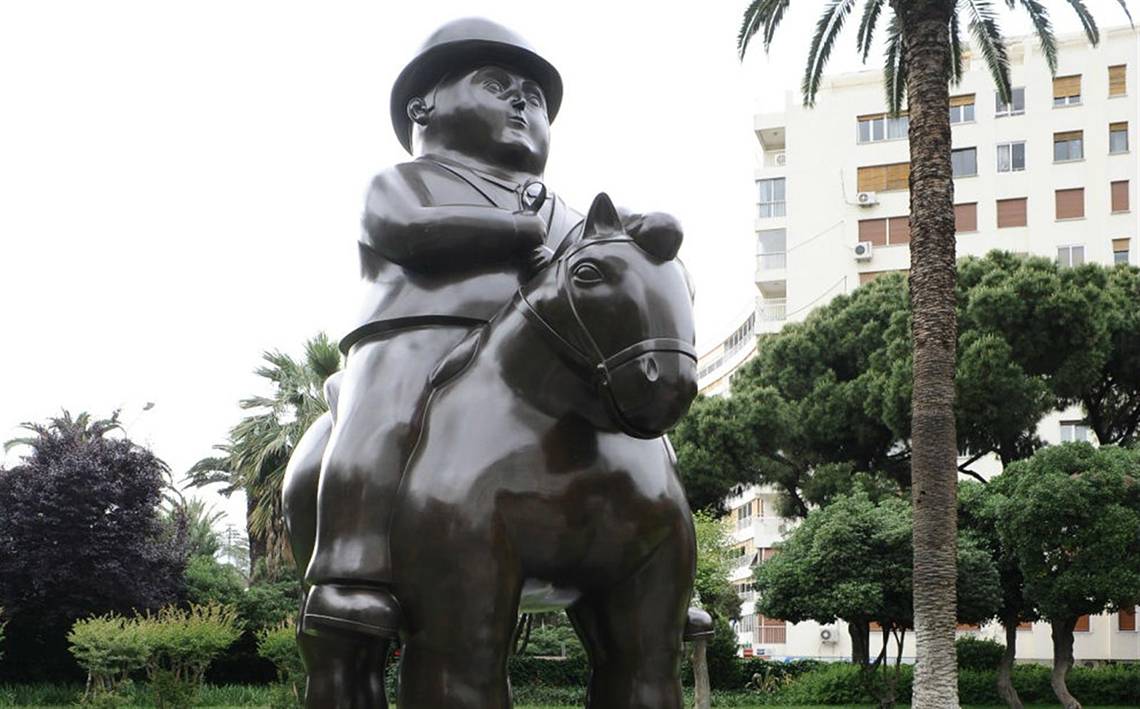 Bronzestatue eines Mannes, der auf einem Pferd im Park reitet, vor einem Gebäude mit vielen Fenstern
