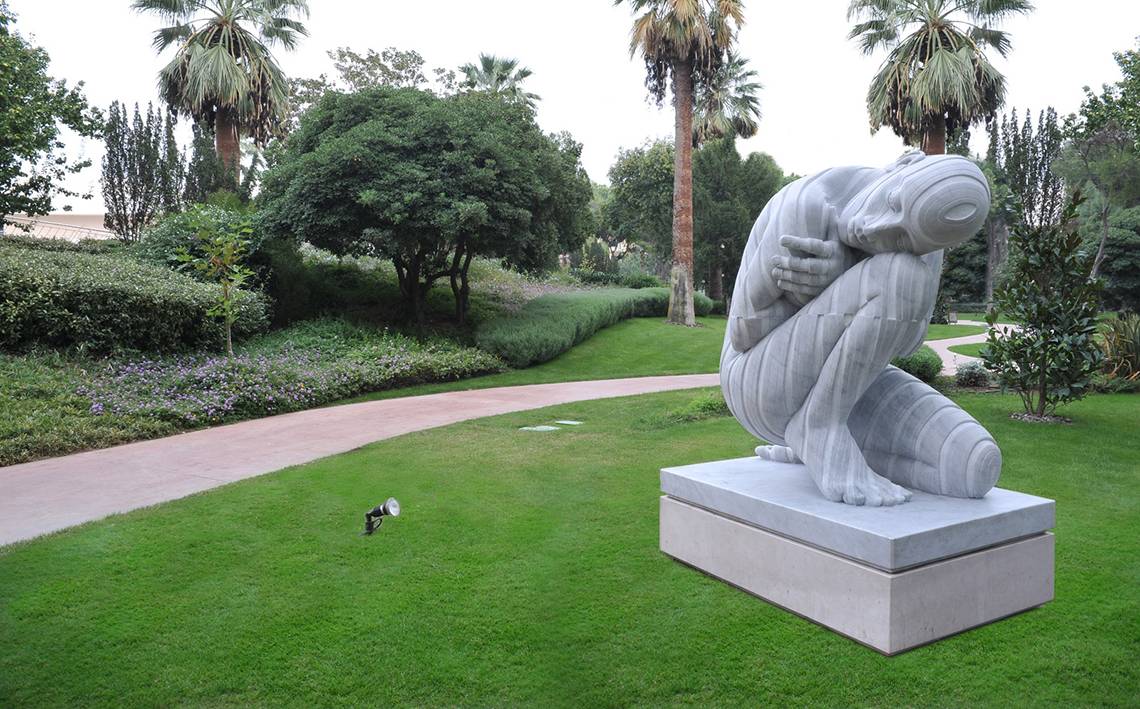 Große Skulptur im Garten neben einem Pfad und Palmen