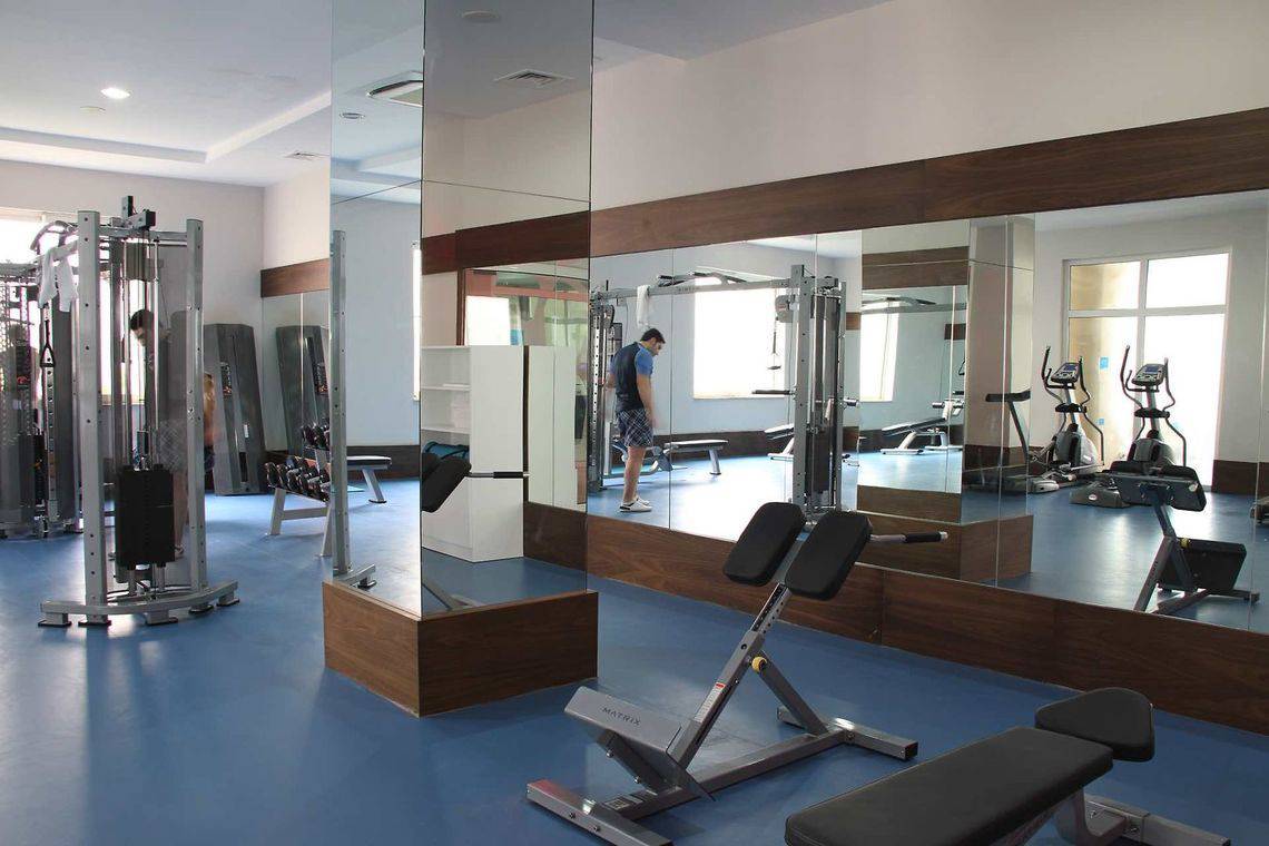 Fitnessstudio im Adalya Ocean Deluxe Hotel mit Spiegeln und Trainingsgeräten.