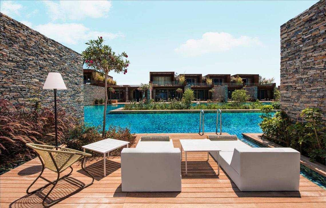 Pool-Loungebereich im Maxx Royal Kemer Resort mit weißen Möbeln und einer steinernen Umgebung.