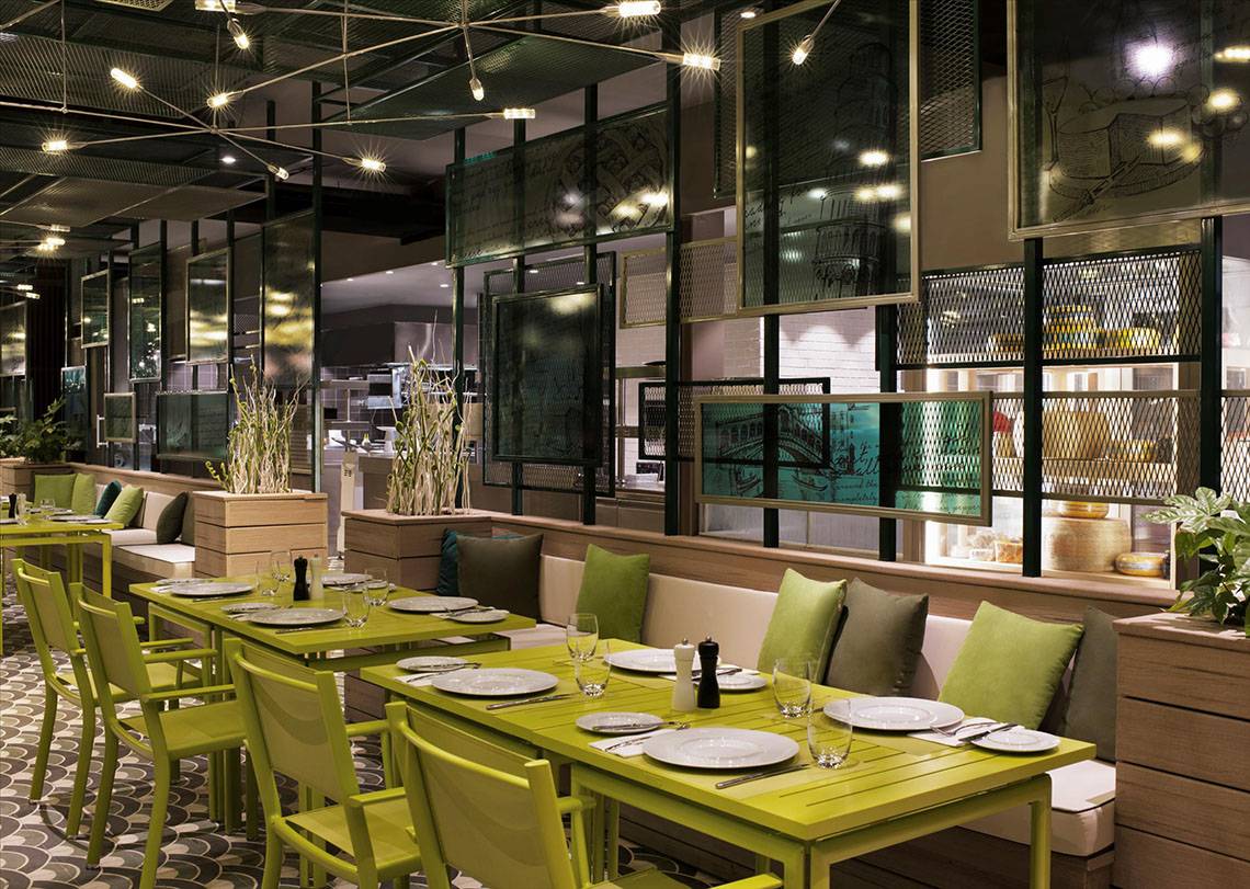 Innenbereich des Restaurants im Maxx Royal Kemer Resort mit grünen Tischen und Stühlen.