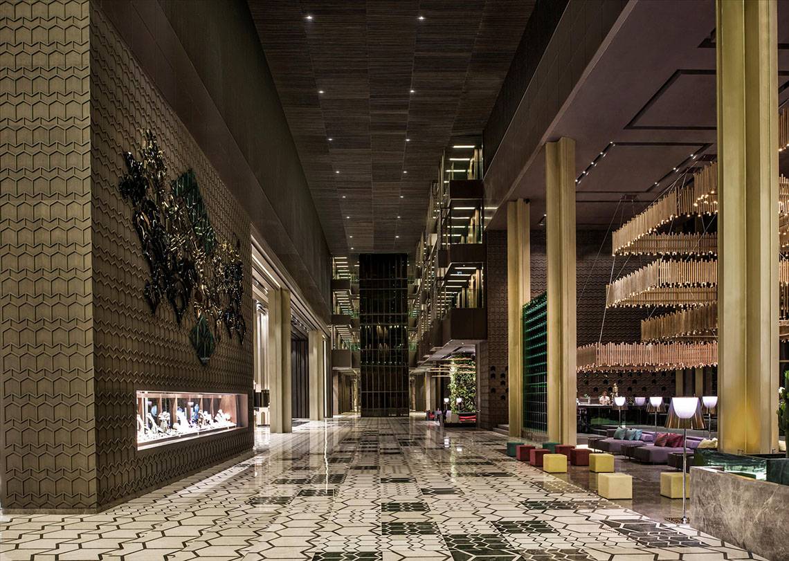 Innenbereich des Maxx Royal Kemer Resorts mit geometrischen Mustern, goldenen Säulen und Kronleuchtern.