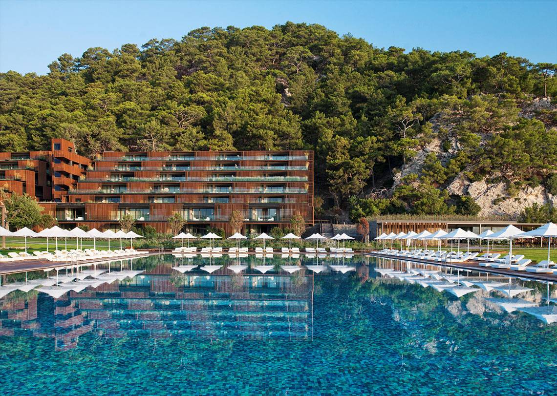Außenbereich des Maxx Royal Kemer Resorts mit großem Pool und Sonnenliegen.