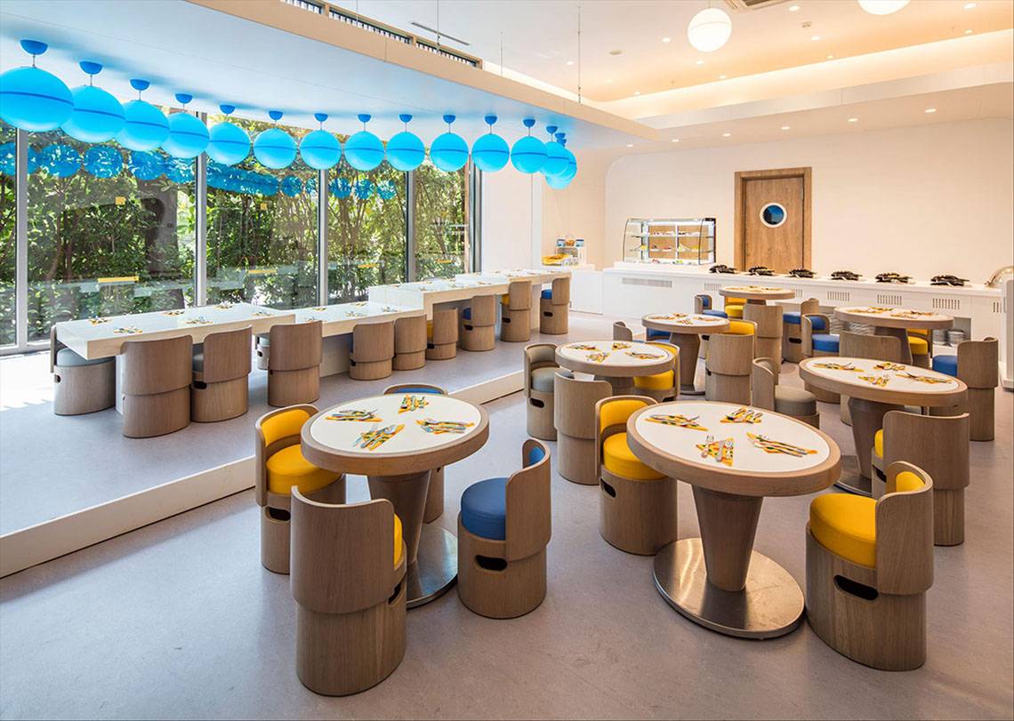 Innenbereich des Maxx Royal Kemer Resort mit mehreren Tischen und Stühlen, blauen Lichtern und großen Fenstern.