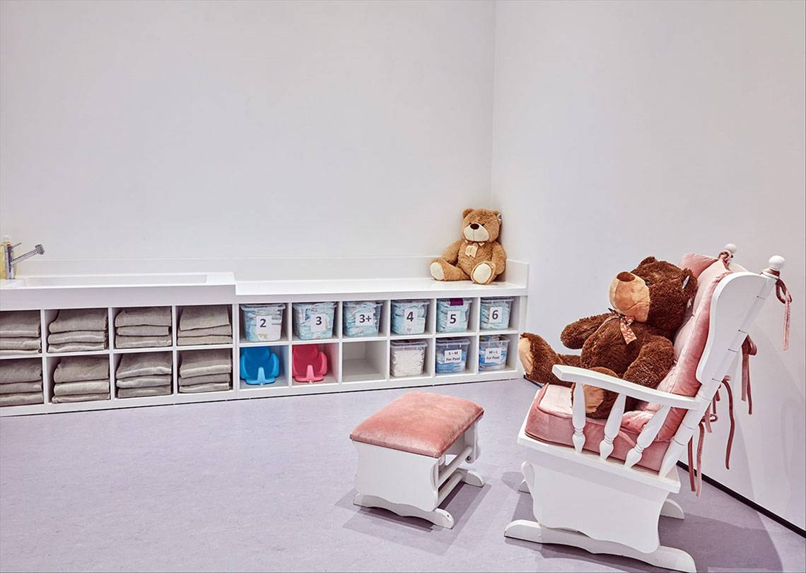 Ein kinderzimmer im Maxx Royal Kemer Resort mit einem weißen schaukelstuhl, einem hocker, truhen und teddybären.